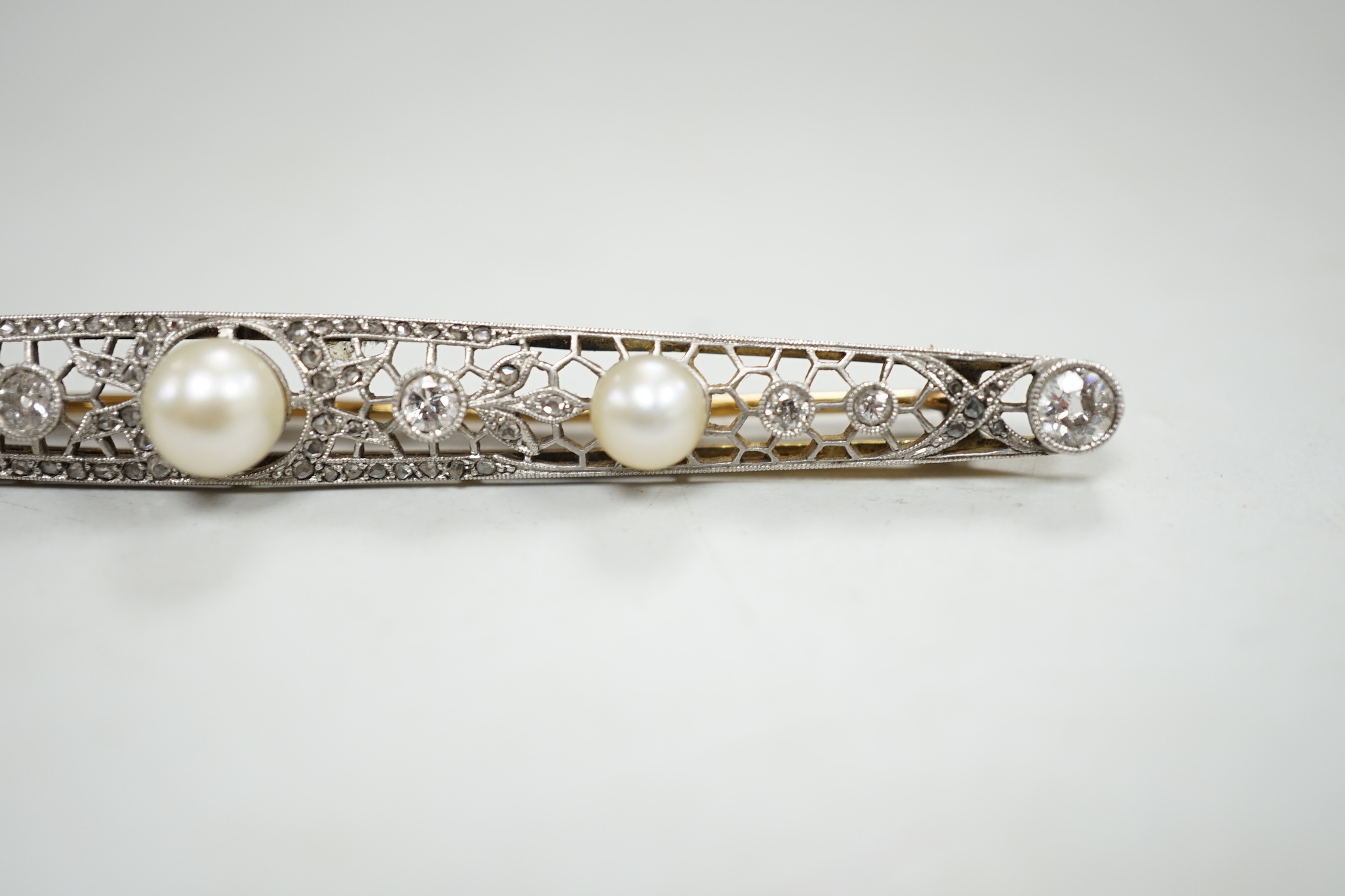 A Belle Epoque pierced yellow and white metal, cultured? pearl and diamond set bar brooch, 84mm, gross weight 10 grams, in fitted leather box.